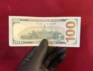 Backside of fake $100 bill showing realistic counterfeit USD features including Independence Hall and security elements
